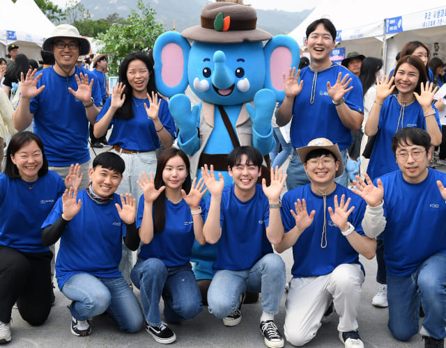 At the Samsung Blue Elephant event, volunteers are waving their hands and taking photos with the Samsung Blue Elephant mascot.