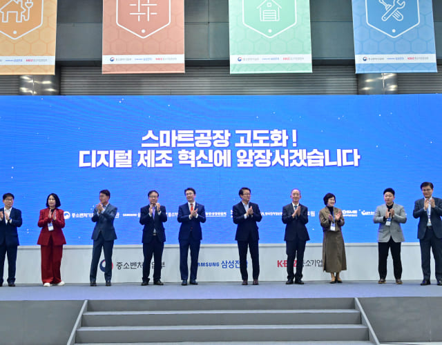 Officials from the Ministry of SMEs and Startups, Samsung, and the Korea Federation of SMEs standing are applauding on stage at the Smart Biz Expo event.