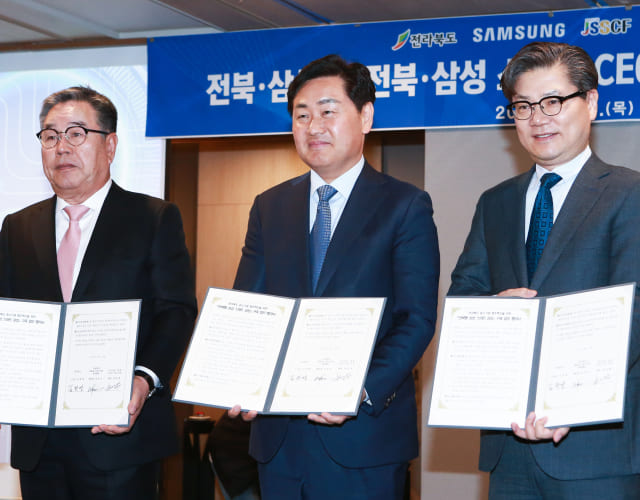 Officials are posing for a commemorative photo while holding the agreement documents at the Samsung Smart Factory agreement ceremony in the Jeonbuk region.