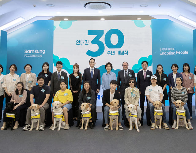 On the occasion of the 30th anniversary of the Samsung Guide Dog program, Jae-Yong Lee, chairman of Samsung Electronics, and Ra-hee Hong, former director of the Leeum Samsung Museum of Art, are taking a photo with visually impaired individuals, trainers, and volunteers.